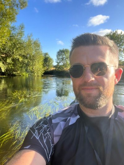 Chris full fibre engineer sat by a lake wearing sunglasses