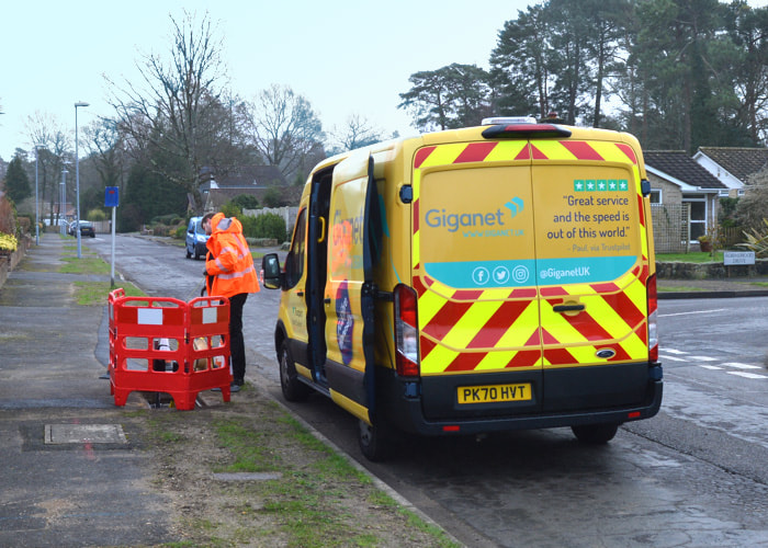 Giganet engineer wearing orange high vis jacket parked on side of road in Tadley installing full fibre broadband.