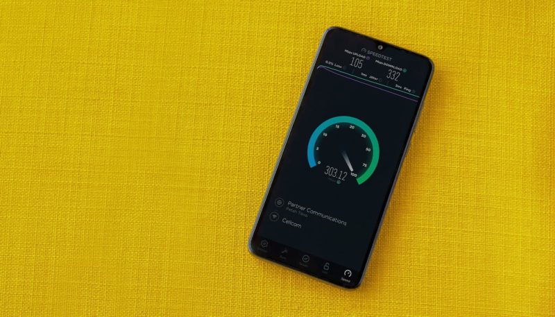 Smartphone on yellow table showing full fibre broadband speed test results